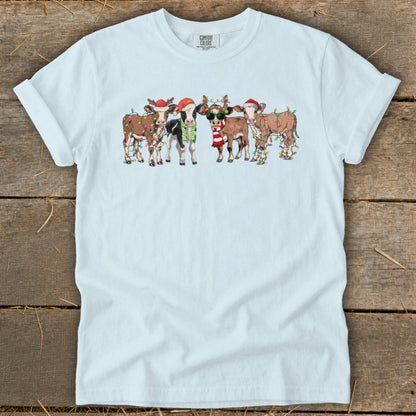 Light blue t-shirt with festive cows wearing Santa hats and Christmas lights.