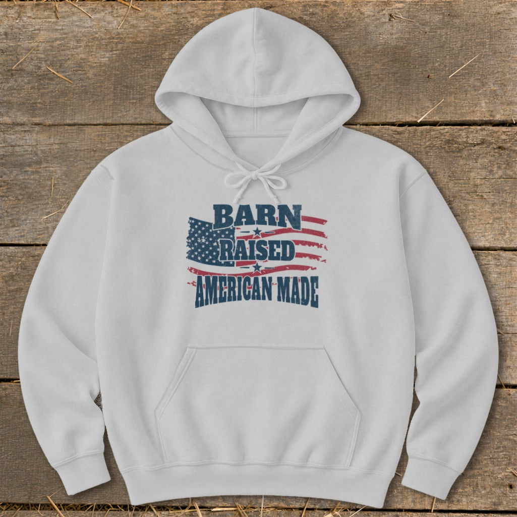 White hoodie with "Barn Raised American Made" text and distressed American flag graphic.