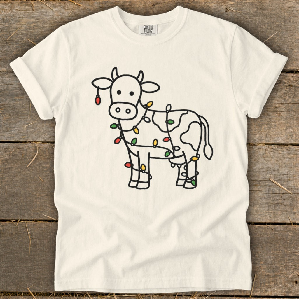 White t-shirt with a cartoon cow outline decorated with colorful Christmas lights.