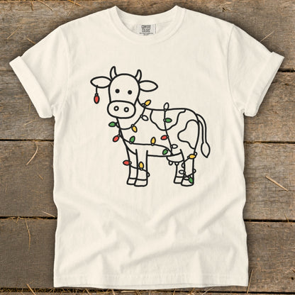 White t-shirt with a cartoon cow outline decorated with colorful Christmas lights.