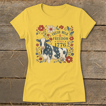 Cow with American flag pattern on yellow t-shirt, text reads "Fresh Milk & Freedom Since 1776".