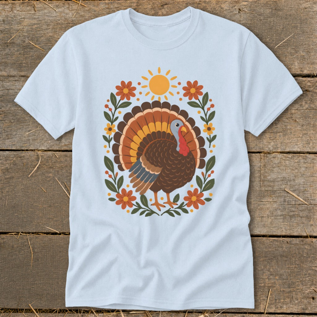 Light blue t-shirt with a cartoon turkey surrounded by flowers and a sun.