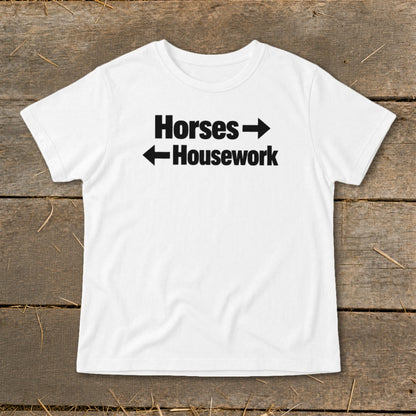 A white t-shirt with black text that reads Horses with a right arrow and Housework with a left arrow.