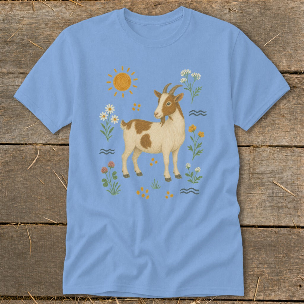 Light blue t-shirt with a brown and white goat surrounded by flowers and sun.