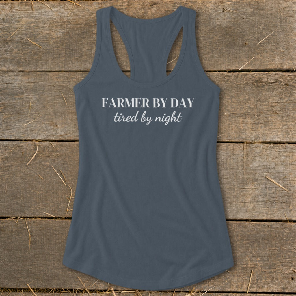 Gray racerback tank top with white text that says "FARMER BY DAY tired by night".