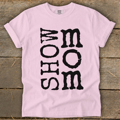 Pink t-shirt with vertical black text reading "MOM" and horizontal text "SHOW".