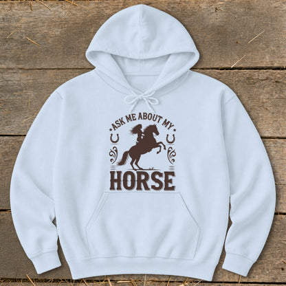 Light blue hoodie with brown graphic featuring a rider on a horse and text "ASK ME ABOUT MY HORSE".