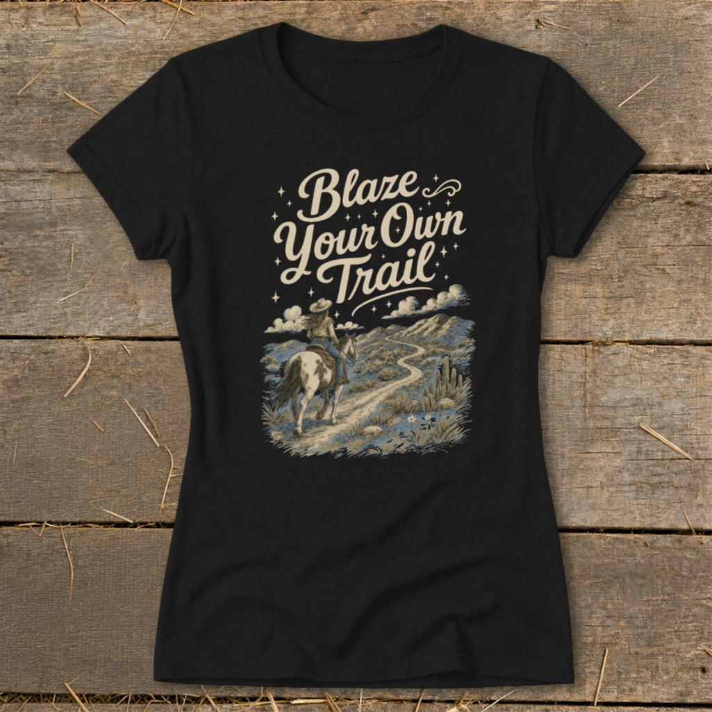 Black t-shirt with "Blaze Your Own Trail" text and a cowboy on horseback in a desert landscape.