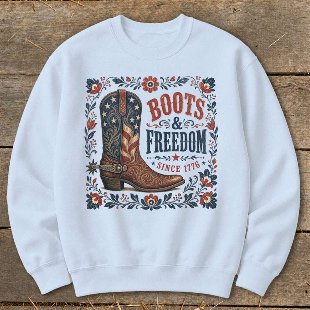 White sweatshirt featuring a cowboy boot with American flag design and text "Boots & Freedom Since 1776."