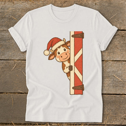Cartoon cow wearing a Santa hat peeking from behind a barn door.