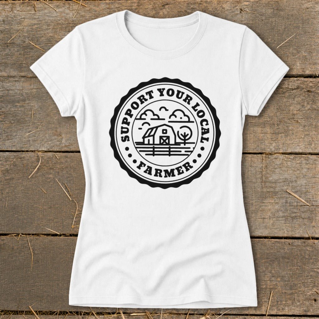 White t-shirt with black circular graphic reading "Support Your Local Farmer" and depicting a barn, trees, and clouds.