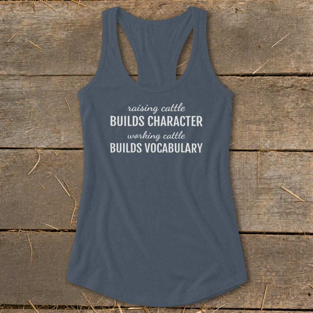 Gray racerback tank top with white text that reads "raising cattle BUILDS CHARACTER working cattle BUILDS VOCABULARY."