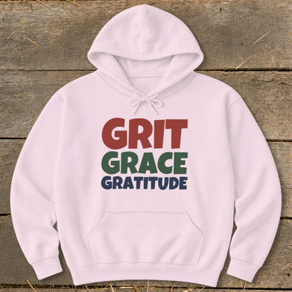 A light pink hooded sweatshirt with the words Grit, Grace, Gratitude printed across the chest.
