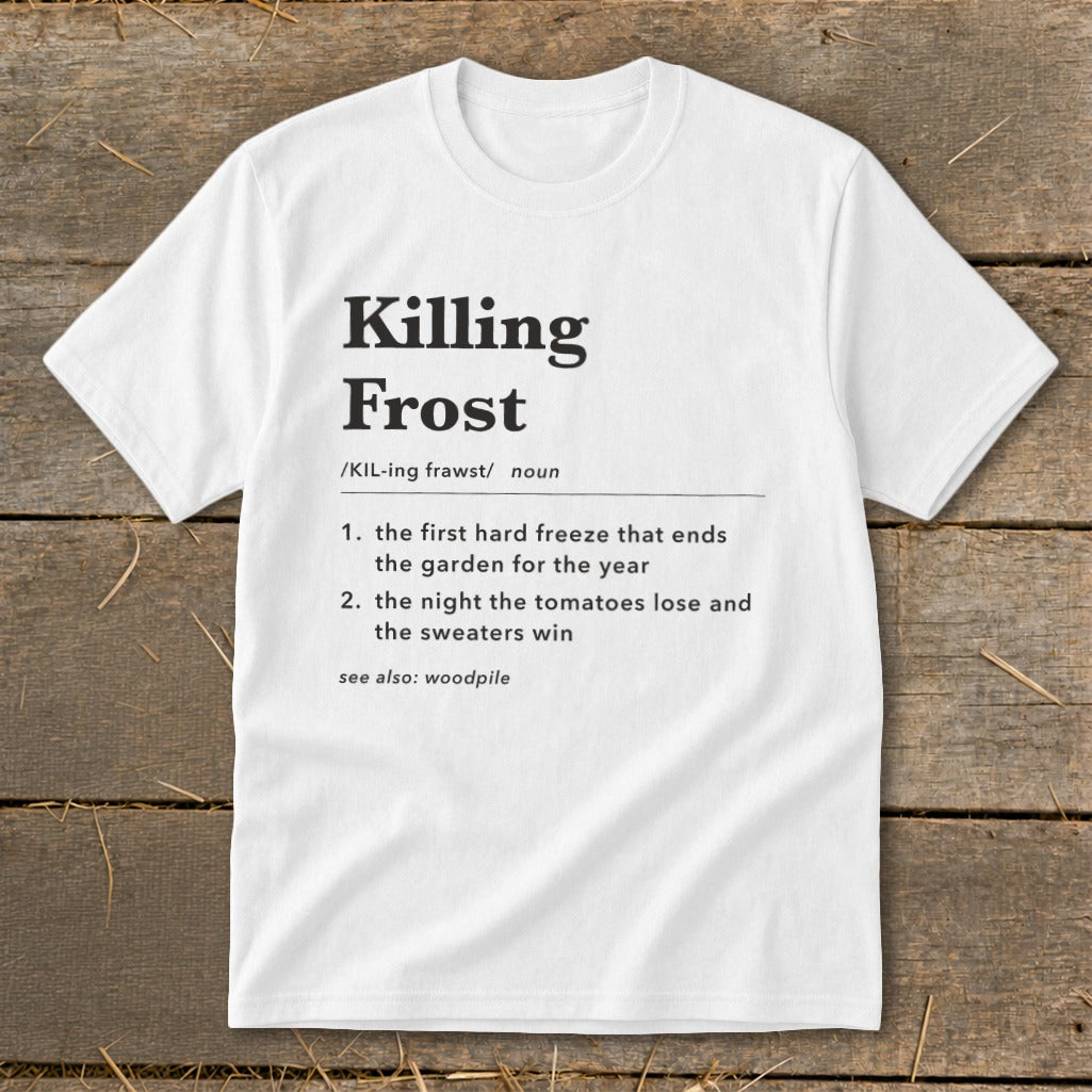 A white t-shirt printed with a dictionary definition of Killing Frost against a rustic wooden background.