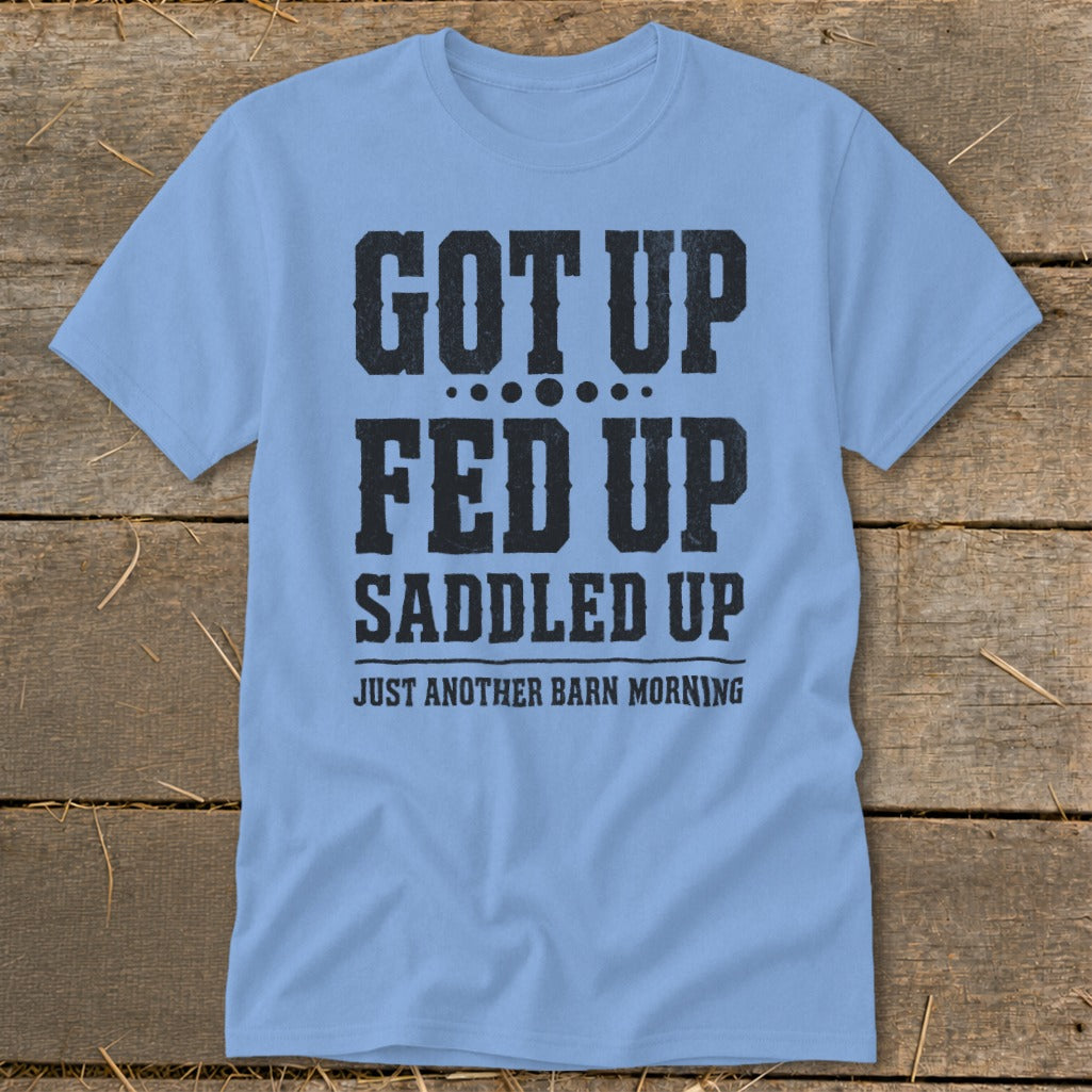 Light blue t-shirt with black text that reads "GOT UP FED UP SADDLED UP JUST ANOTHER BARN MORNING".