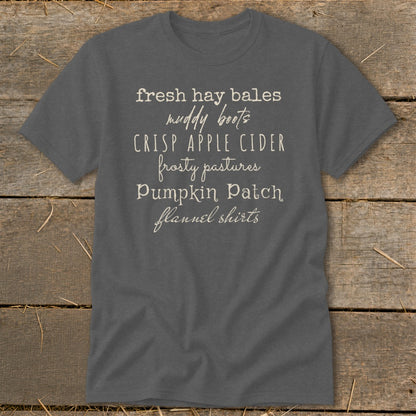 Gray t-shirt with text listing fall themes: "fresh hay bales, muddy boots, crisp apple cider, frosty pastures, pumpkin patch, flannel shirts."