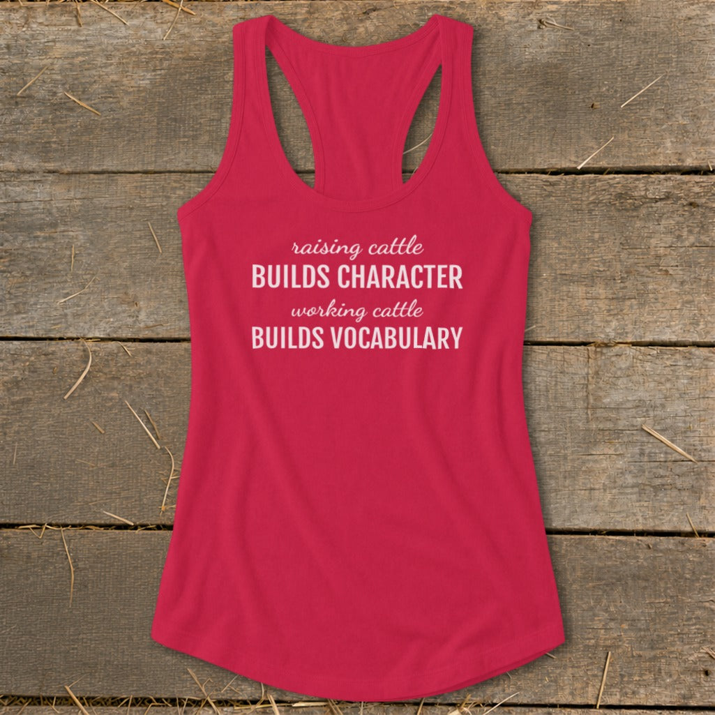 Red racerback tank top with white text reading "raising cattle BUILDS CHARACTER working cattle BUILDS VOCABULARY."