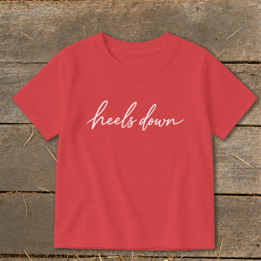 Red t-shirt with "heels down" in white cursive text.