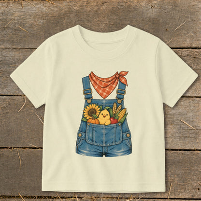Cream t-shirt with illustration of a chick in denim overalls filled with fall harvest.