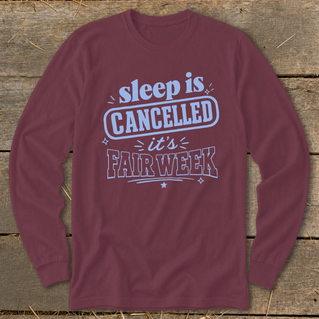 Maroon long-sleeve t-shirt with light blue text reading "sleep is CANCELLED it's FAIR WEEK".