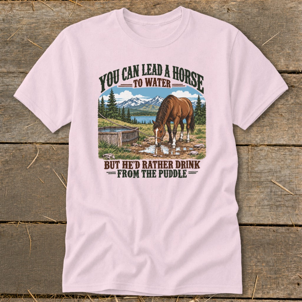 Light pink t-shirt featuring a graphic of a horse drinking from a puddle with mountains behind it.