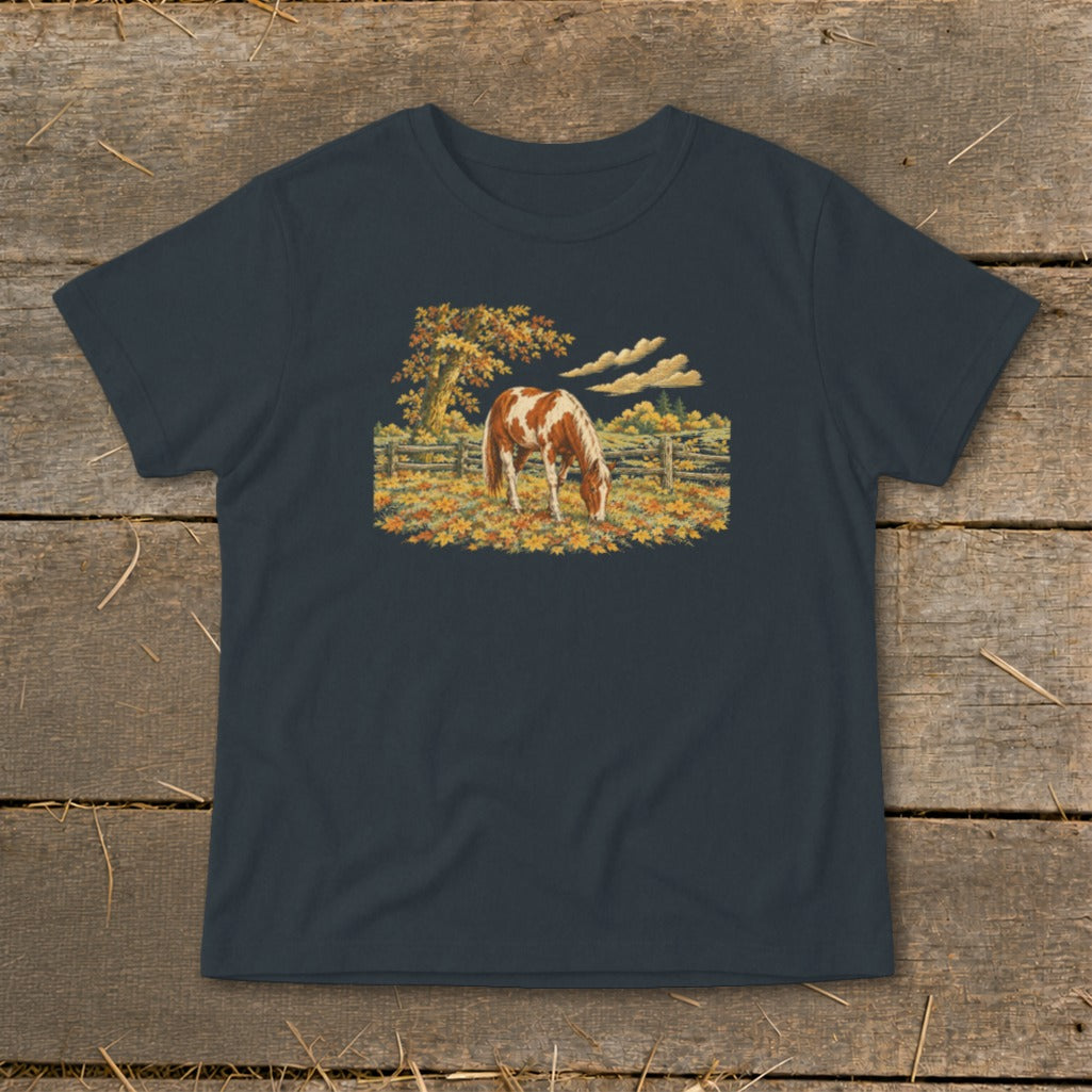 Brown and white horse grazing in a field of autumn leaves and hay.