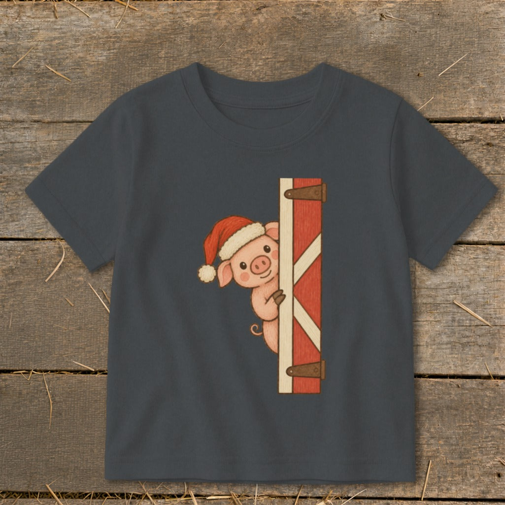 Pig wearing a Santa hat peeks from behind a barn door.