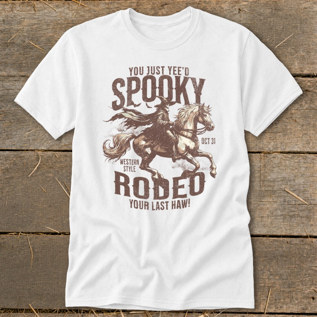 White t-shirt with distressed graphic of a witch riding a horse and text "Spooky Rodeo Your Last Haw!"
