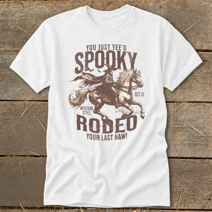White t-shirt with distressed graphic of a witch riding a horse and text "Spooky Rodeo Your Last Haw!"