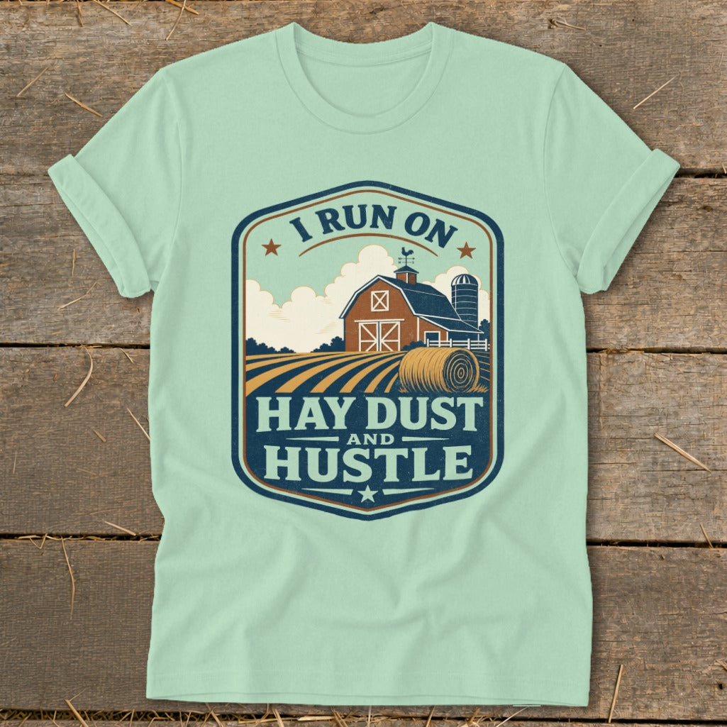 Light blue t-shirt with a farm graphic and "I Run on Hay Dust and Hustle."