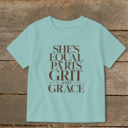 Light blue t-shirt with brown text that reads "She's Equal Parts Grit and Grace".