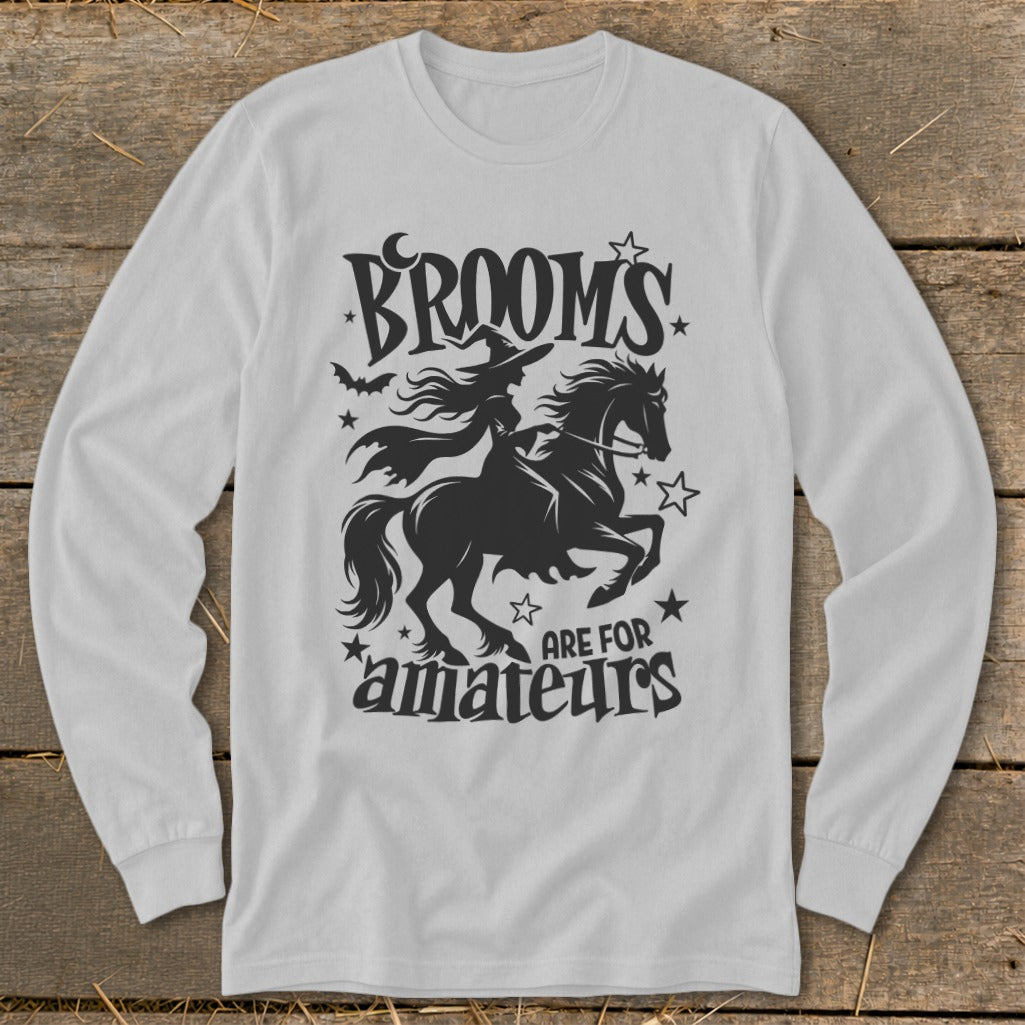 Black graphic on white long-sleeve shirt: witch riding horse, text "Brooms are for amateurs".