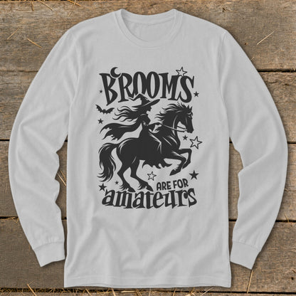 Black graphic on white long-sleeve shirt: witch riding horse, text "Brooms are for amateurs".