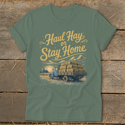 Green t-shirt with "Haul Hay or Stay Home" text and illustration of a blue truck hauling hay.