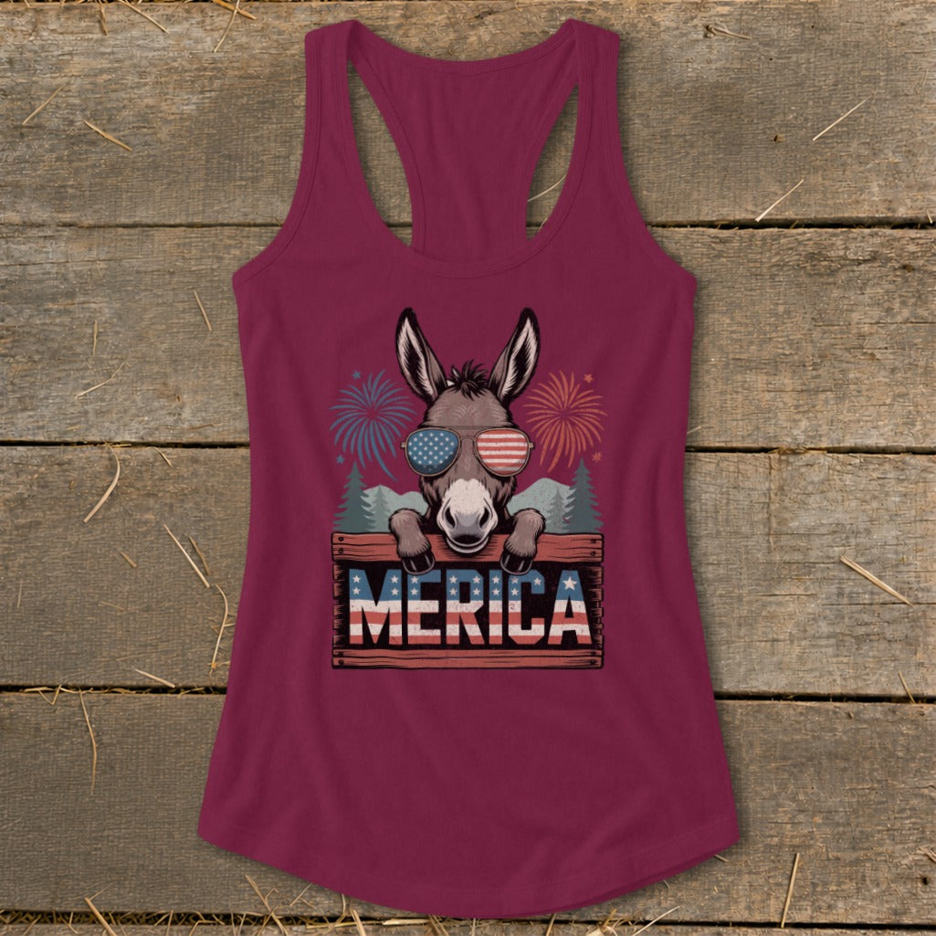 Donkey wearing American flag sunglasses and "MERICA" sign with fireworks background.