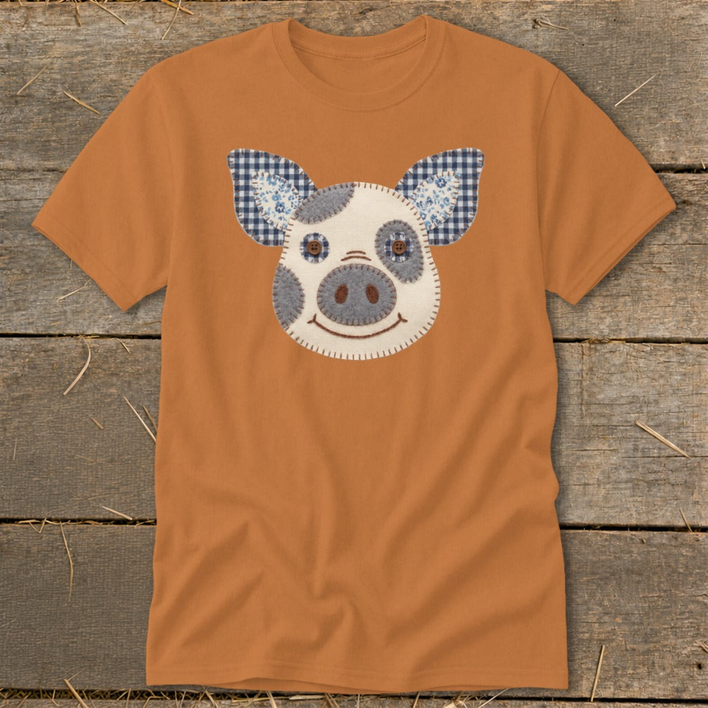 Orange t-shirt with a stitched pig face applique and checkered ears.