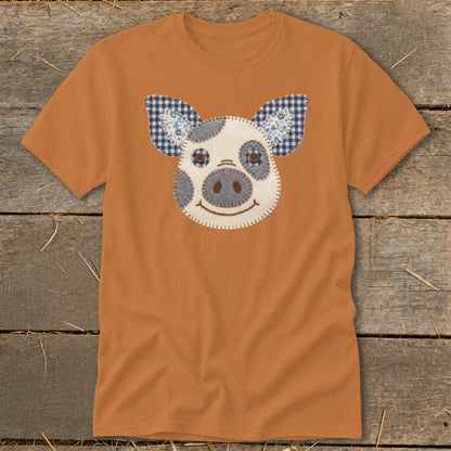 Orange t-shirt with a stitched pig face applique and checkered ears.