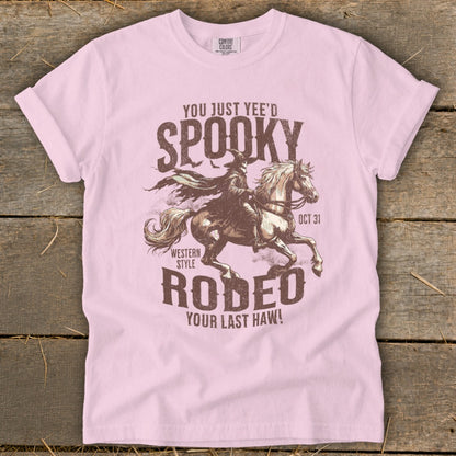 Pink t-shirt with "Spooky Rodeo" graphic of a cowboy riding a horse, dated Oct 31.