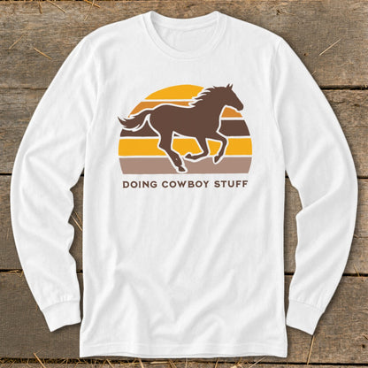 White long sleeve shirt with a brown horse silhouette and text "DOING COWBOY STUFF."
