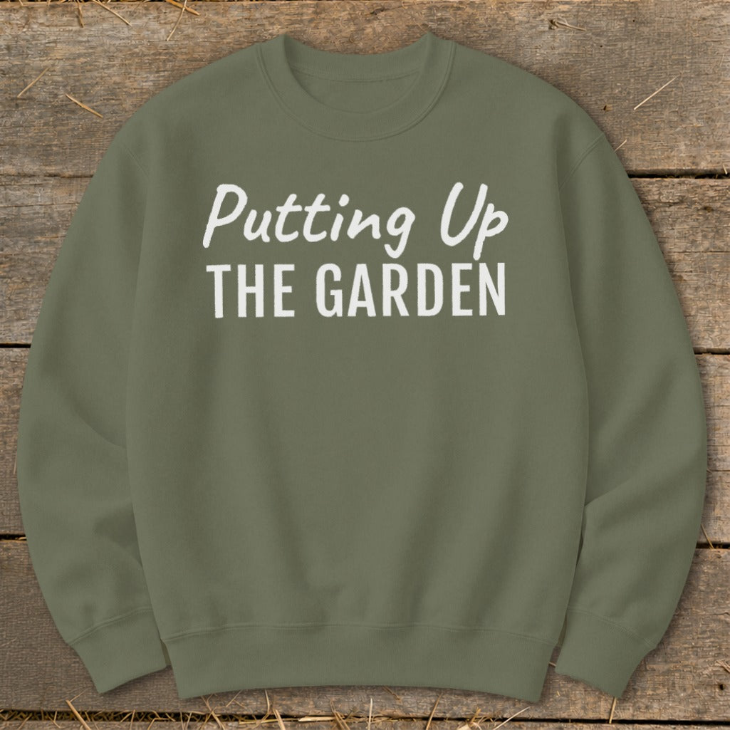 Olive green sweatshirt with white text reading "Putting Up THE GARDEN".