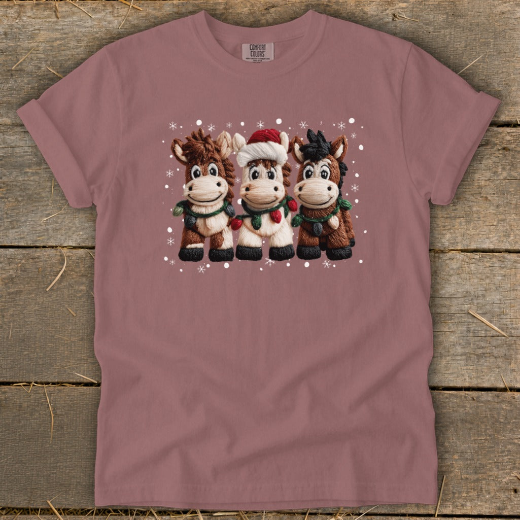 Three cartoon horses in Christmas attire with snowflakes.