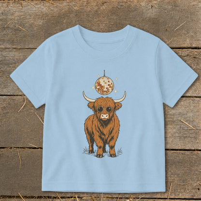 Highland cow wearing sunglasses with disco ball above on light blue shirt.