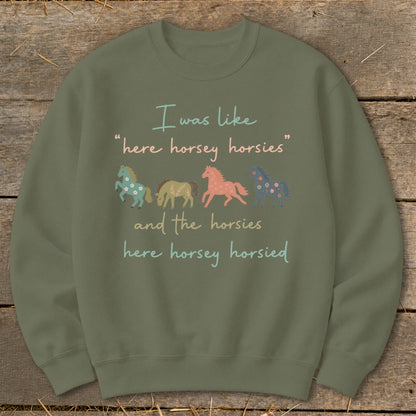 Green sweatshirt with text and four illustrated horses, two floral.