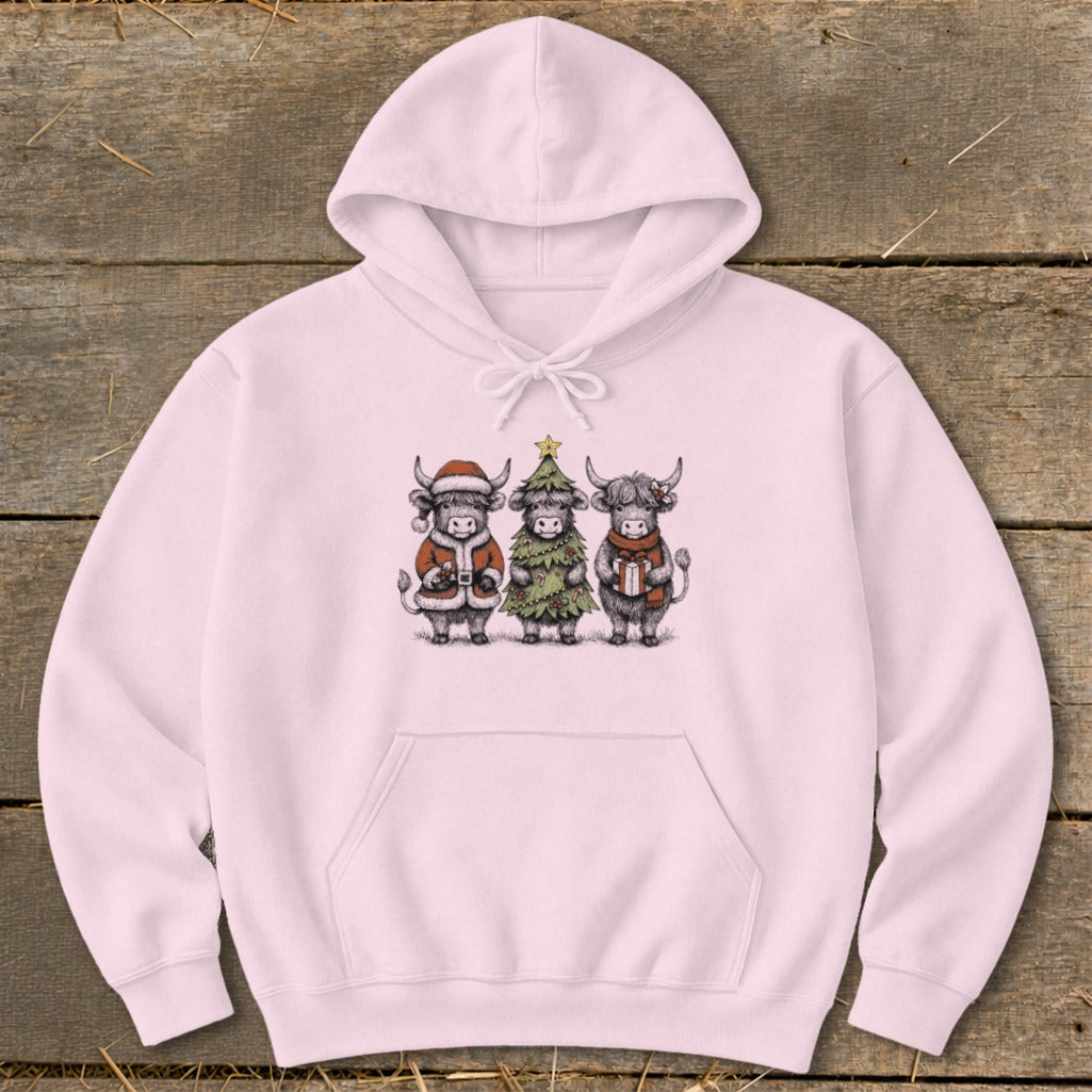 Pink hoodie with a Christmas-themed drawing of three highland cows.