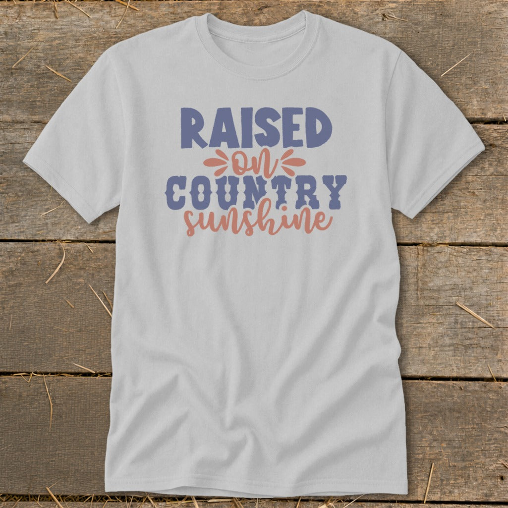 Light gray t-shirt with "RAISED ON COUNTRY SUNSHINE" text in blue and pink.