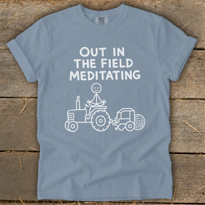 T-shirt with "Out in the field meditating" text and a stick figure meditating on a tractor.