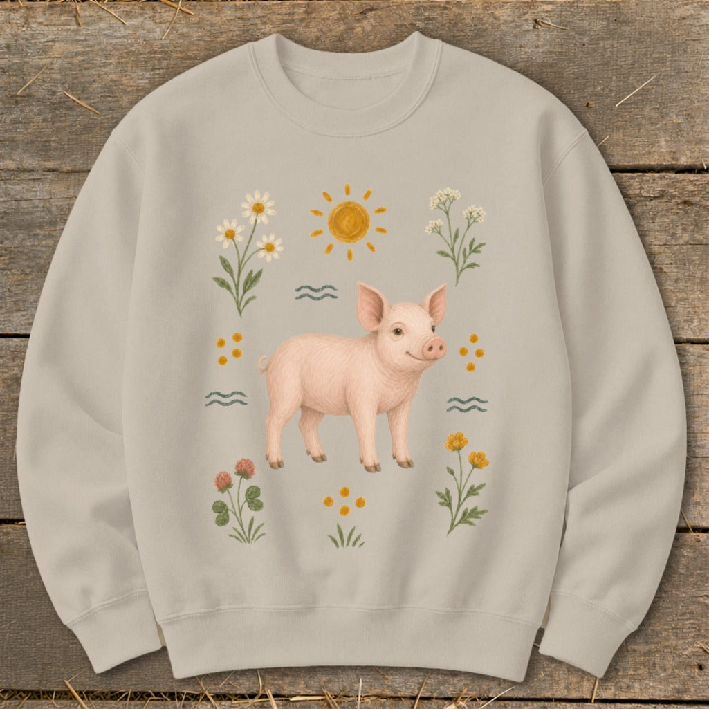 Light beige sweatshirt with a smiling pink pig surrounded by flowers and a sun.