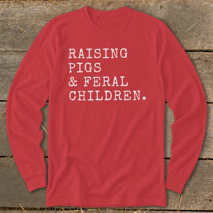 Red long-sleeve shirt with white text "RAISING PIGS & FERAL CHILDREN."