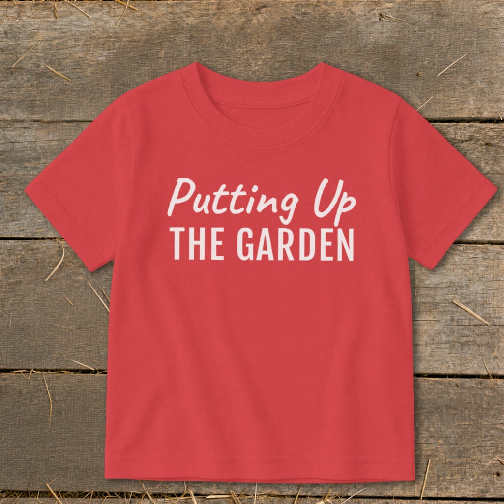 Red t-shirt with white text "Putting Up THE GARDEN".