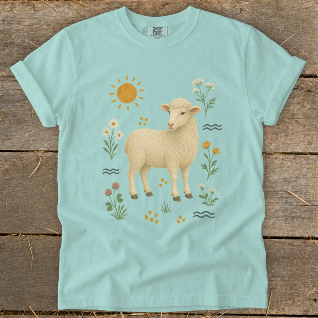 Light blue t-shirt with a cream-colored sheep and floral meadow graphic.